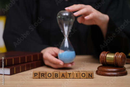 Tableau sur toile A judge holds an hourglass filled with blue sand, symbolizing time in a courtroom setting