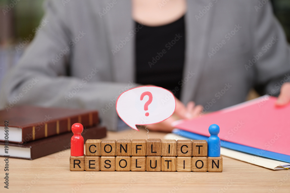Naklejka premium Individuals engage in a thoughtful dialogue about conflict resolution using colorful figures and blocks on a wooden table. Files and legal books hint at a serious discussion.