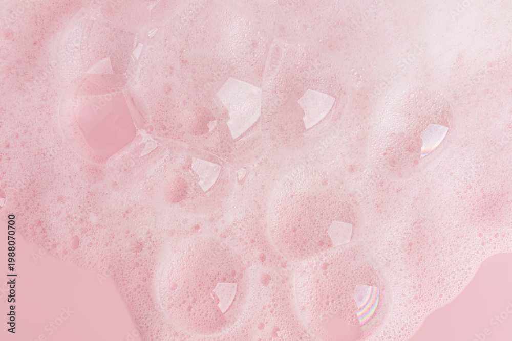 Fototapeta premium Large transparent soap bubbles, soft foam of soap, gel, detergent on a pink background. Hygiene and cleanliness concept. Top view. A copy space