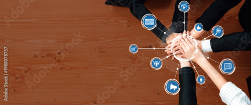 Tableau sur toile A powerful image of teamwork depicts diverse hands joining together on a wooden table, surrounded by digital icons symbolizing communication, strategy, and connection in business