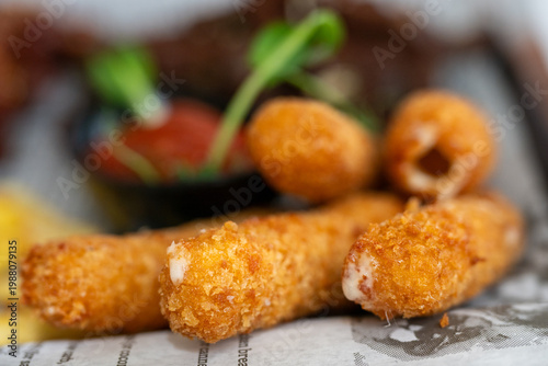 Photos crispy golden fried mozzarella cheese sticks resting on newspaper-style paper, w