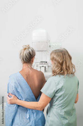 фотографія 50-year-old woman undergoes mammography procedure on special medical equipment mammograph with help of assistant in modern clinic