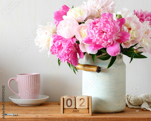 July 2. the date of the summer day or holiday event. a calendar and a bouquet of garden peonies in the cottage.