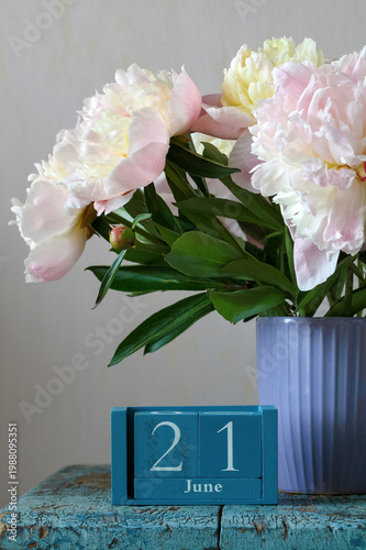June 21st. calendar and bouquet of garden peonies in a violet mug. summer holiday, event or deadline.