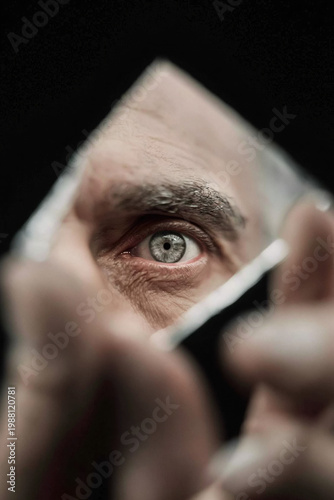 Reflective gaze through broken mirror: eye and fragments of life captured in a intense moment