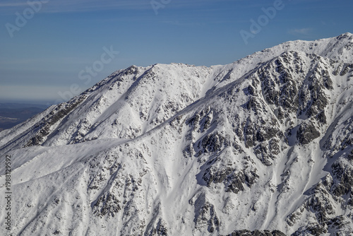 Snow-covered mountains stand tall under a blue sky in a winter landscape during midday. Tatra mountain, Zakopane, Poland