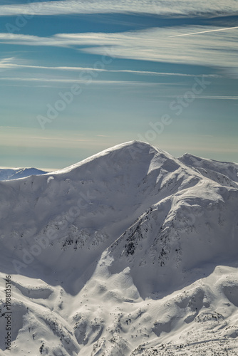 Snow-covered mountain range under a clear blue sky near a popular hiking trail in winter with no signs of people around. Tatra mountains, Zakopane, Poland.