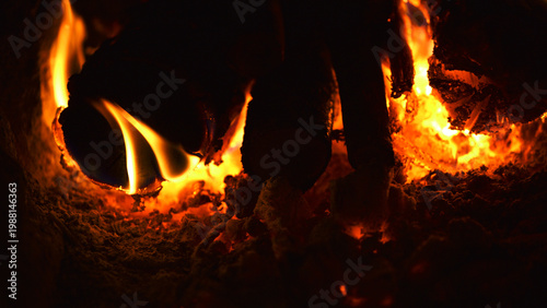 firewood burns, fire coals at night. Red hot coals glowing. Orange glow from the coals at the stake at night. flames on a black background. Close-up of flame in fireplace, warmth and comfort