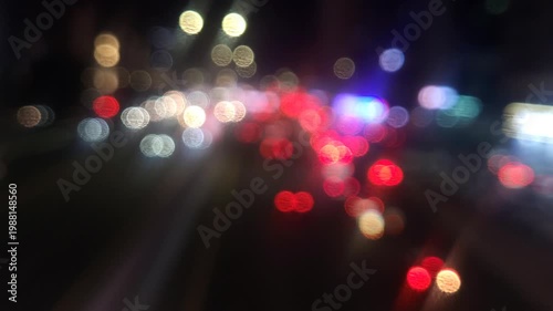 Defocused city traffic lights at night with cars passing by