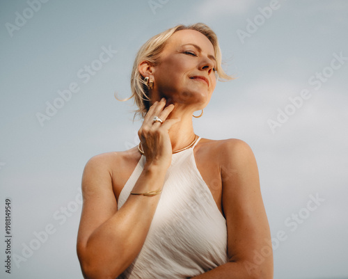 Elegant woman wearing luxurious gold jewelry with serene outdoor background