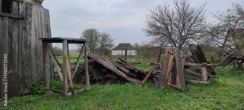 Old wooden barn and pile of weathered planks in a rural backyard.