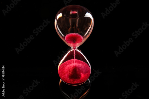 Φωτογραφία Crystal hourglass with red sand on dark background