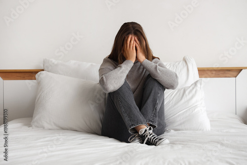 Photography Sad young woman sitting in bedroom