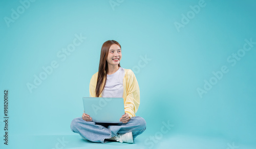 Obraz na płótnie Young Asian Woman Sitting with Laptop Smiling and Thinking with Copy Space