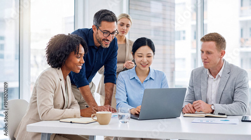 Canvas Print Diverse team of business professionals collaboratively reviewing data on a laptop during an engaging meeting in