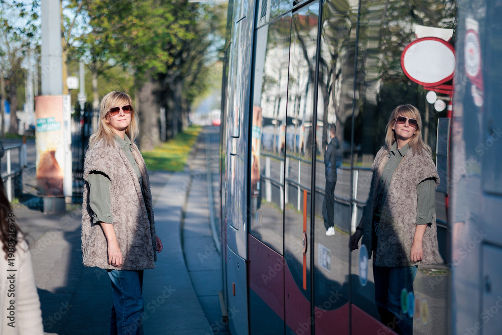 Obraz premium Woman waiting for tram at public transport stop