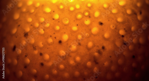 Macro photograph of an orange peel, showcasing its textured surface with circular pores and speckled details under warm lighting