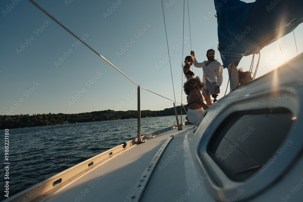 Naklejka premium Friends enjoying sailing trip on yacht at sunset