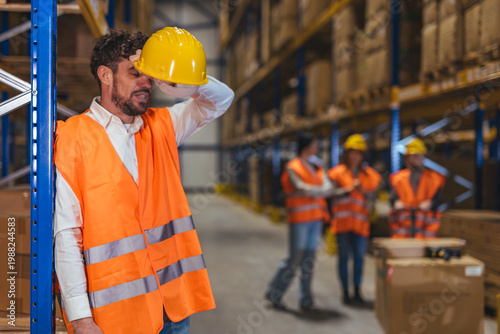 Warehouse Worker Exhausted Removing Hard Hat After Long Shift in Industrial Storage Facility