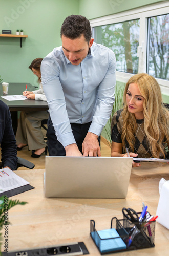 Business professional couple collaborating and discussing a contract issues on a laptop screen, analyzing data and charts during a busy day at modern coworking office space. Problems at work concept.
