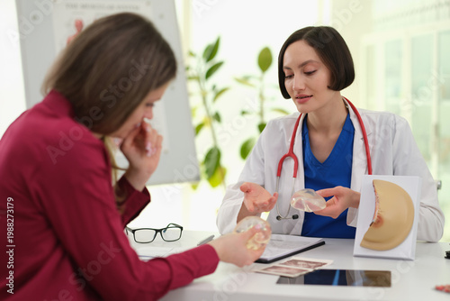 In a bright consultation room, a woman discusses breast augmentation with a healthcare provider.