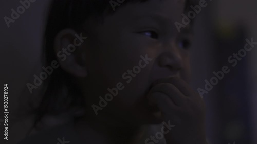 Toddler Holds Peeled Apple Ready To Bite, A cute toddler in a baby suit chews on fingers, wide eyes gleaming under soft light, perfect for family photography shot or playful innocence showcase.