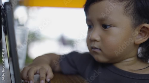 Toddler Is Sitting Watching Kids Songs On Mobile Phone, A sweet film of toddler sitting watching kids songs, big eyes fixed on screen with smiles, modern childhood film or digital documentary.