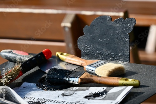 Slika na platnu Close-up of dirty paint brushes and tools covered in black paint on a workspace during renovation or art project