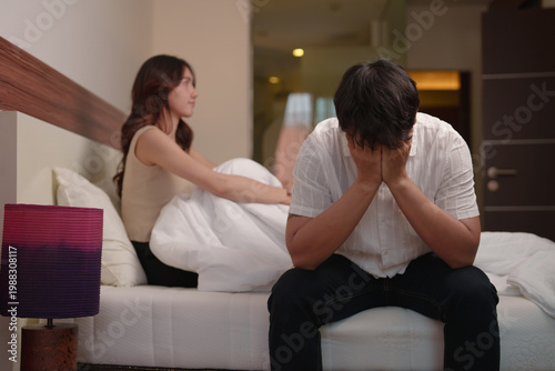 Obraz na płótnie Upset man sitting on bed, covering face, experiencing sadness and stress, while