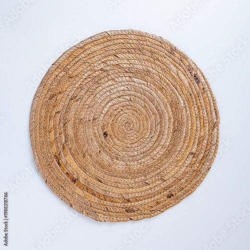 White Ceramic Plate with Silver Cutlery on Brown Round Woven Placemat Isolated on White Background