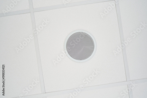Circular loudspeaker embedded in white suspended ceiling