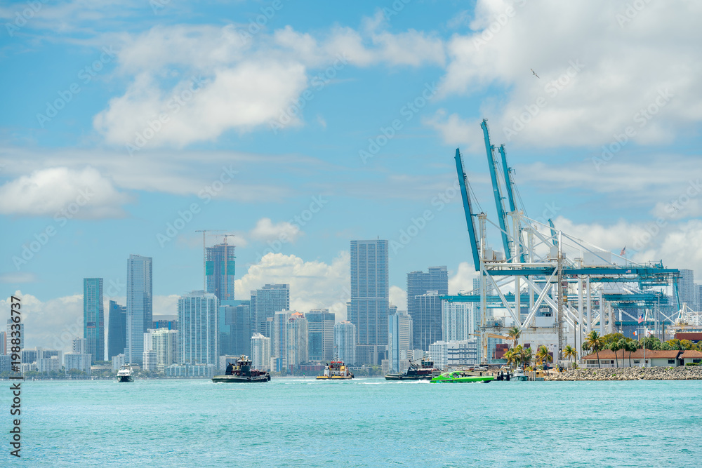Obraz premium Dynamic harbor scene with tugboats and Miami city skyline. Wide angle shot of multiple boats in Miami harbor with a background of skyscrapers and port infrastructure.