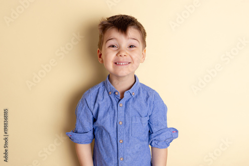 Boy of three years in a blue shirt on a yellow background. Emotional portrait.