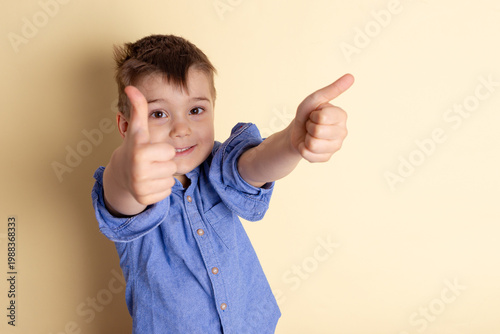 Boy of three years in a blue shirt on a yellow background. Emotional portrait.