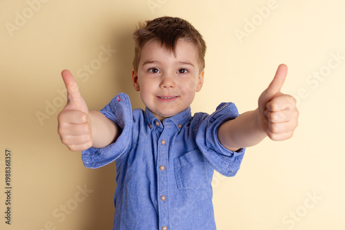 Boy of three years in a blue shirt on a yellow background. Emotional portrait.