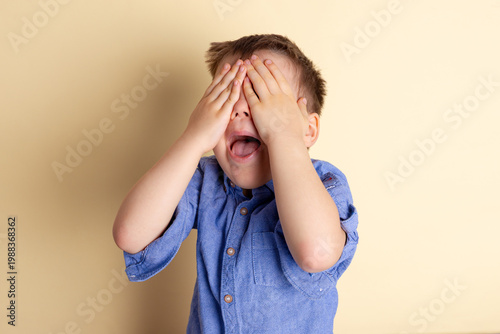 Boy of three years in a blue shirt on a yellow background. Emotional portrait.