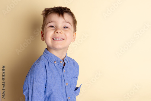 Boy of three years in a blue shirt on a yellow background. Emotional portrait.