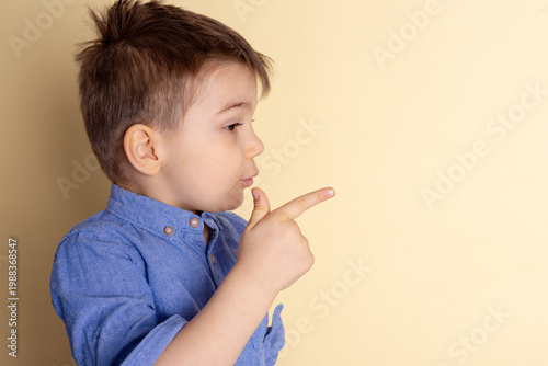 Boy of three years in a blue shirt on a yellow background. Emotional portrait.