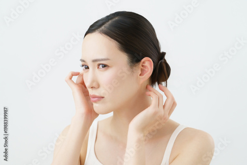 白背景の頭を触る若い日本人女性