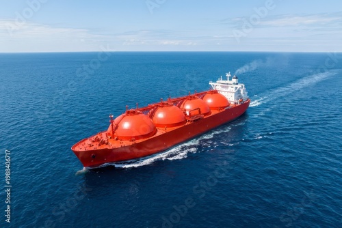 Red LNG carrier ship sailing on calm ocean under clear blue sky transporting natural gas