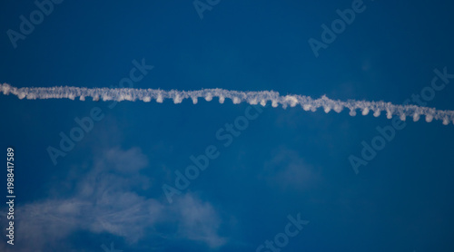 Close-up of Crow Instability in Aircraft Contrail against Blue Sky. Detailed view of a persistent condensation trail.