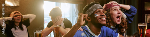 Fotografía Multiethnic young adults watching sports match in bar, cheering and reacting with excitement, expressing fan engagement and group entertainment