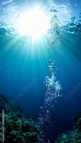 Beneath the surface, the bright sun illuminates a cluster of bubbles rising from unseen depths against a vibrant blue backdrop