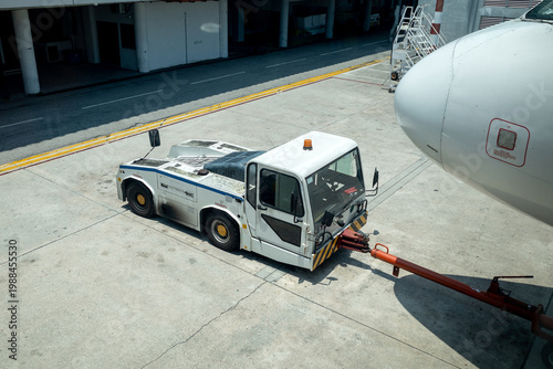 Canvas Print View of an aircraft tug with its arm attached to an aircraft on the tarmac of an