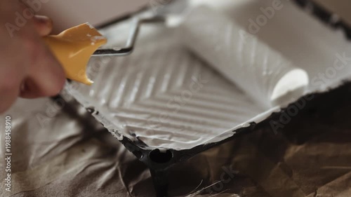 Close-up of Paint Roller Dipped into White Paint in Tray, Preparing for Wall or Door Painting, 4K 10-bit
