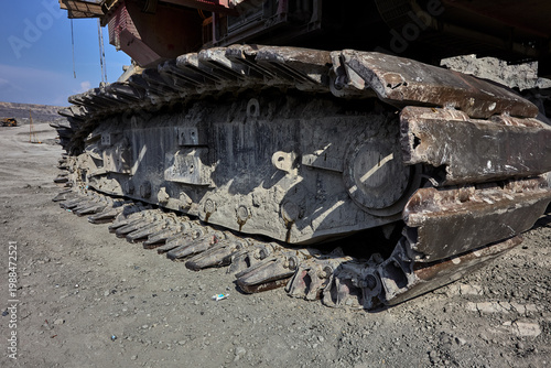 The iron foundation of a mining giant — a dramatic low-angle perspective reveals the massive steel crawler tracks of an electric rope shovel, each individual link forged to carry hundreds of tonnes 