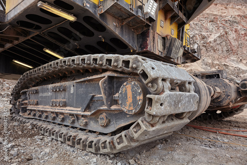 The iron foundation of a mining giant — a dramatic low-angle perspective reveals the massive steel crawler tracks of an electric rope shovel, each individual link forged to carry hundreds of tonnes 
