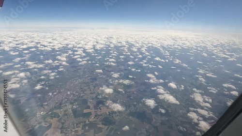 Aerial view from airplane window showing clouds and landscape below symbolizing travel freedom and exploration.