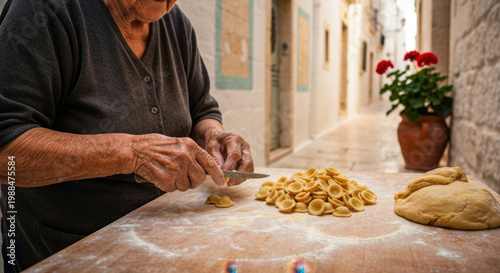 Elderly Apulian woman skillfully crafting traditional Orecchiette pasta by hand in a sunlit cobblestone alleyway in Bari Vecchia, Italy
