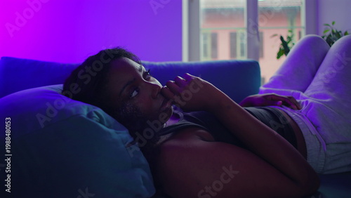 Fotografie African American woman lying on couch looking toward camera with thoughtful expr